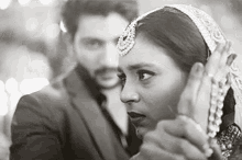 a man and a woman are holding hands and looking at each other in a black and white photo .