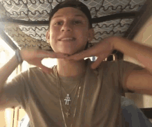 a young man wearing a necklace with a cross on it is making a funny face