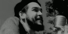 a man with a beard singing into a microphone in a black and white photo