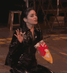 a woman in a catsuit holding a bag of chips