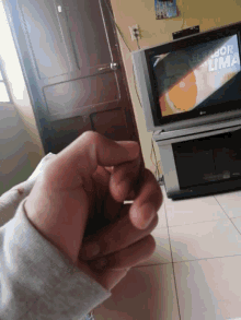 a person 's hand is in front of an lg television