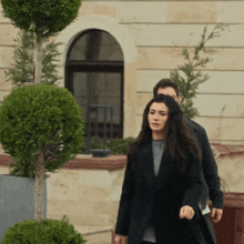 a woman in a black coat is walking with a man in a black jacket