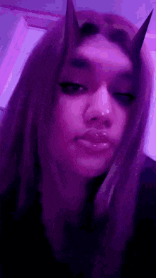 a woman with horns on her head is wearing a purple mask .