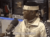 a man is sitting in front of a microphone wearing a headband that says the club .