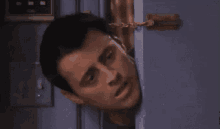 a man is peeking out from behind a door with his eyes wide open .