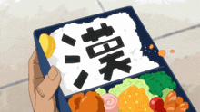 a person is holding a bento box with chinese characters on the rice