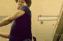 a man wearing a cowboy hat stands in front of a shelf