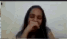 a woman is covering her mouth with her hand while talking on a video call .
