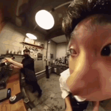 a man 's face is shown in a kitchen while another man stands behind him