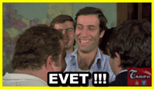 a group of men are laughing and one of them has the word evet on his face
