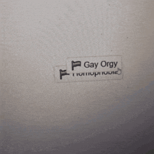 a sticker on a wall that says gay orgy homophobia