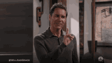 a man in a grey shirt is pointing his finger at the camera with the hashtag #willandgrace