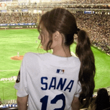 a woman wearing a sana jersey stands in a stadium