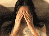 a woman is covering her face with her hands in a bathtub