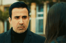 a man with a beard is looking at a woman with a serious look on his face .