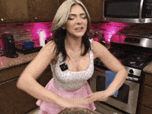 a woman in a pink apron is standing in front of a stove