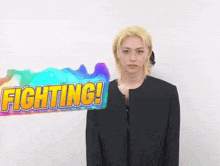 a man with blonde hair is standing next to a sign that says fighting