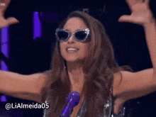 a woman wearing sunglasses is standing in front of a microphone with the hashtag lialmeida05