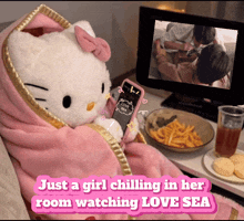 a hello kitty doll is wrapped in a pink blanket and looking at her phone