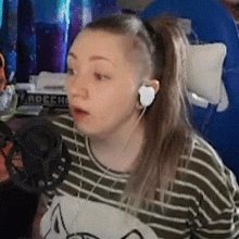 a woman with a ponytail and a shaved head is wearing headphones and a striped shirt .