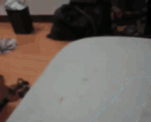 a blurred image of a room with a bed and a trash can .