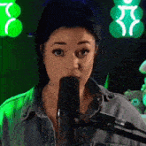 a woman is singing into a microphone and making a funny face