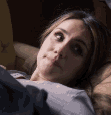 a woman is laying on a couch and making a sad face