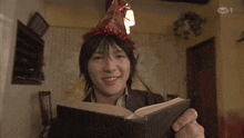 a man wearing a party hat looks at a book