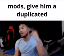 a man in a blue shirt is sitting in front of a computer with the words `` mods , give him a duplicated '' .