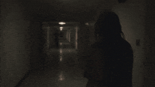 a person walking down a dark hallway with a light on the ceiling
