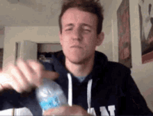 a man in a hoodie is holding a plastic bottle of water