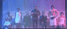 a group of men are standing next to each other on a stage with towels wrapped around their bodies .