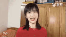 a woman in a red sweater is making a funny face in a room .