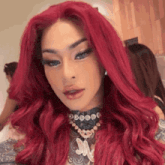 a woman with red hair is wearing a necklace and a wig .