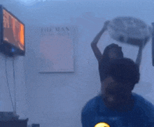 a person is wearing a fan on their head in front of a tv .