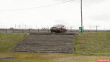 a red car is parked on a set of stairs with thinki jules written on the bottom left