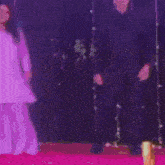 a man in a suit is standing in front of a black wall