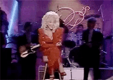 dolly parton is sitting on a stool while playing a guitar on stage