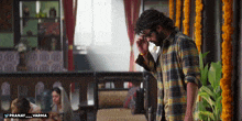 a man in a plaid shirt stands in a room