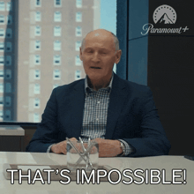 a man in a suit sitting at a table with the words that 's impossible