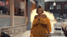 a woman in a yellow dress is walking down a street next to a sign that says today