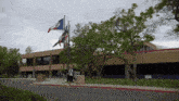 a person walking in front of a building with flags flying in the wind