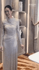 a woman in a long white dress is standing in front of a shelf