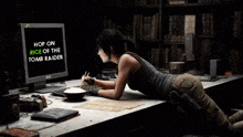 a woman looking at a computer screen that says " hop on rice of the tomb raider "