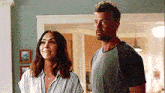 a man and a woman are standing next to each other in a living room looking at something .