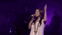 a man is singing into a microphone in a dark purple room .
