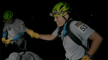 a man wearing a helmet that says petzl on it gives a high five to another man