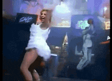 a woman in a white dress is dancing on a stage in front of a sign that says ' dirty dancing '