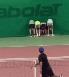 a group of people are standing on a tennis court in front of a babolat banner