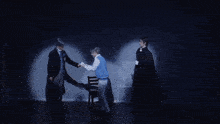 a man in a suit and tie is giving a flower to another man